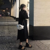 Пальто нового стиля 2025 года с высоким воротником и длинным свитером выше колена с черным трикотажным платьем под ним для осенних и зимних женщин.