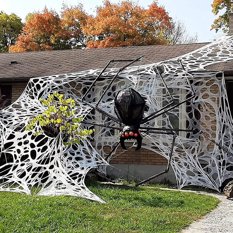Halloween spider web decorations, realistic giant fake plush spiders, outdoor scene decorations for a scary atmosphere.