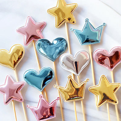 A birthday party featuring baked cakes decorated with shiny stars, crowns, hearts, and cards in four colors: gold, silver, pink, and blue