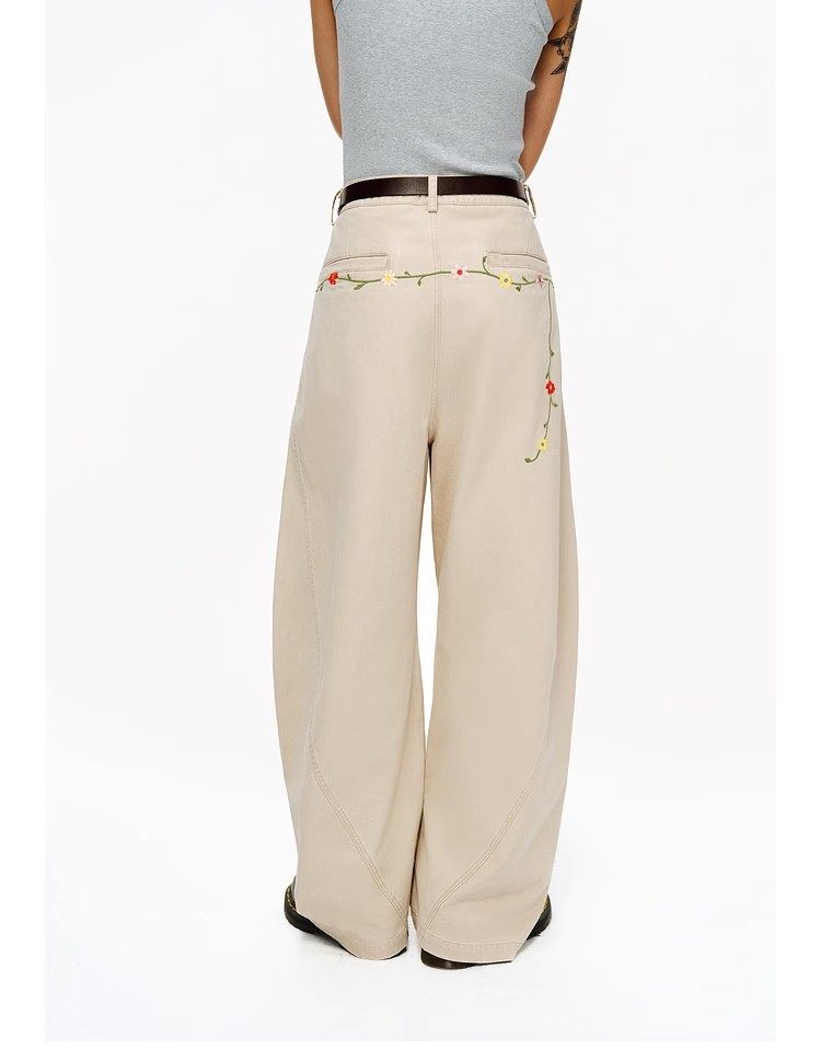 A person models EastLyst’s Floral Embroidery Cargo Pants, featuring wide legs and floral details at the waist, paired with a gray sleeveless top. Only their torso and legs are visible against a plain white background, shown from the back.