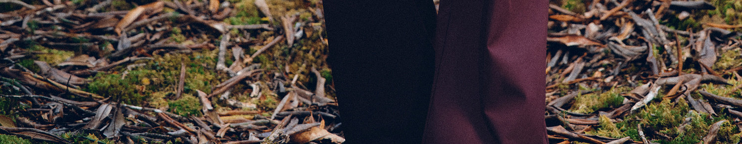Close-up of legs in dark pants on a mossy forest floor, highlighting EastLyst's 3-in-1 Color-Block Storm Jacket—ideal all-weather protection for trails or urban commutes.