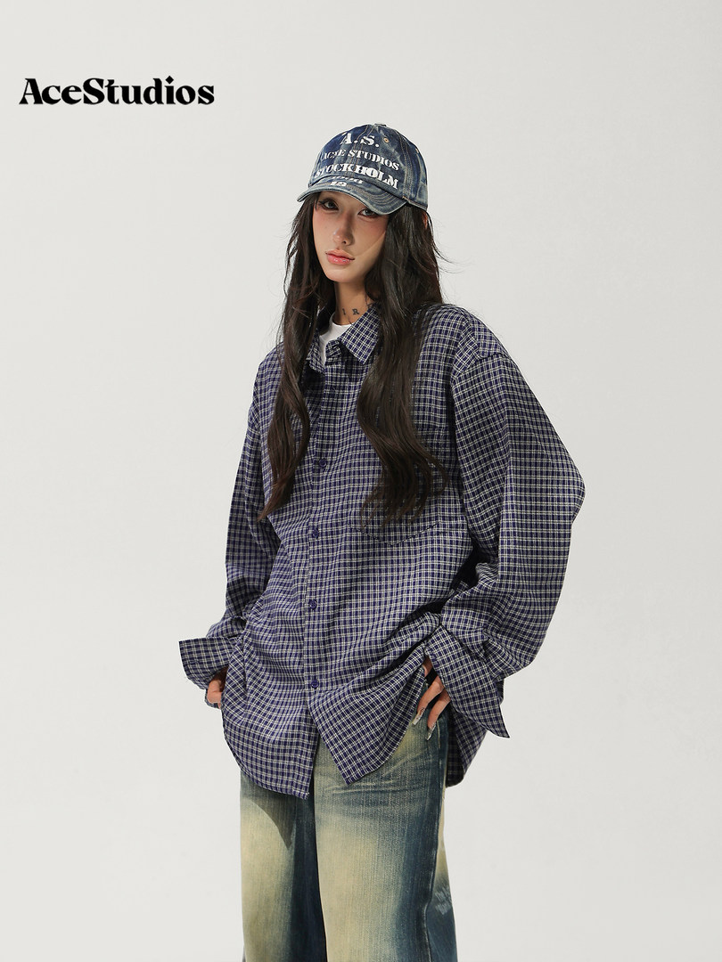 Model wearing an oversized black-and-white plaid shirt, jeans, and a graphic baseball cap.