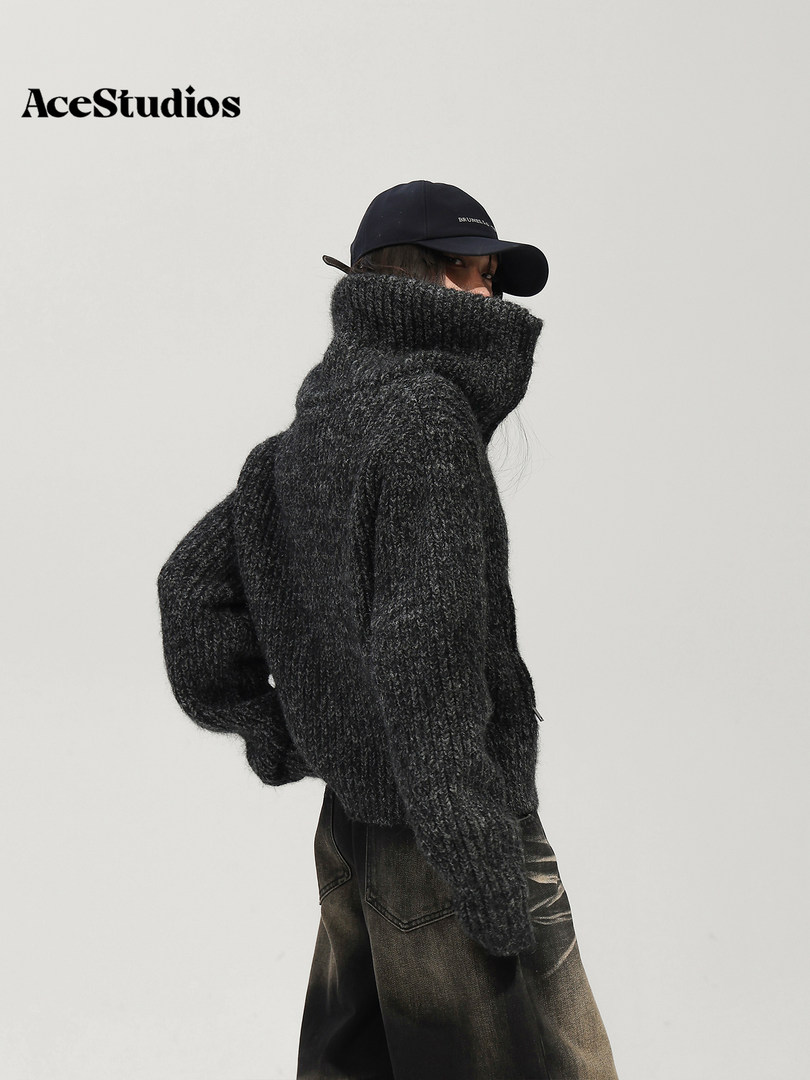 Model wearing an oversized black textured turtleneck sweater with a cap and dark jeans