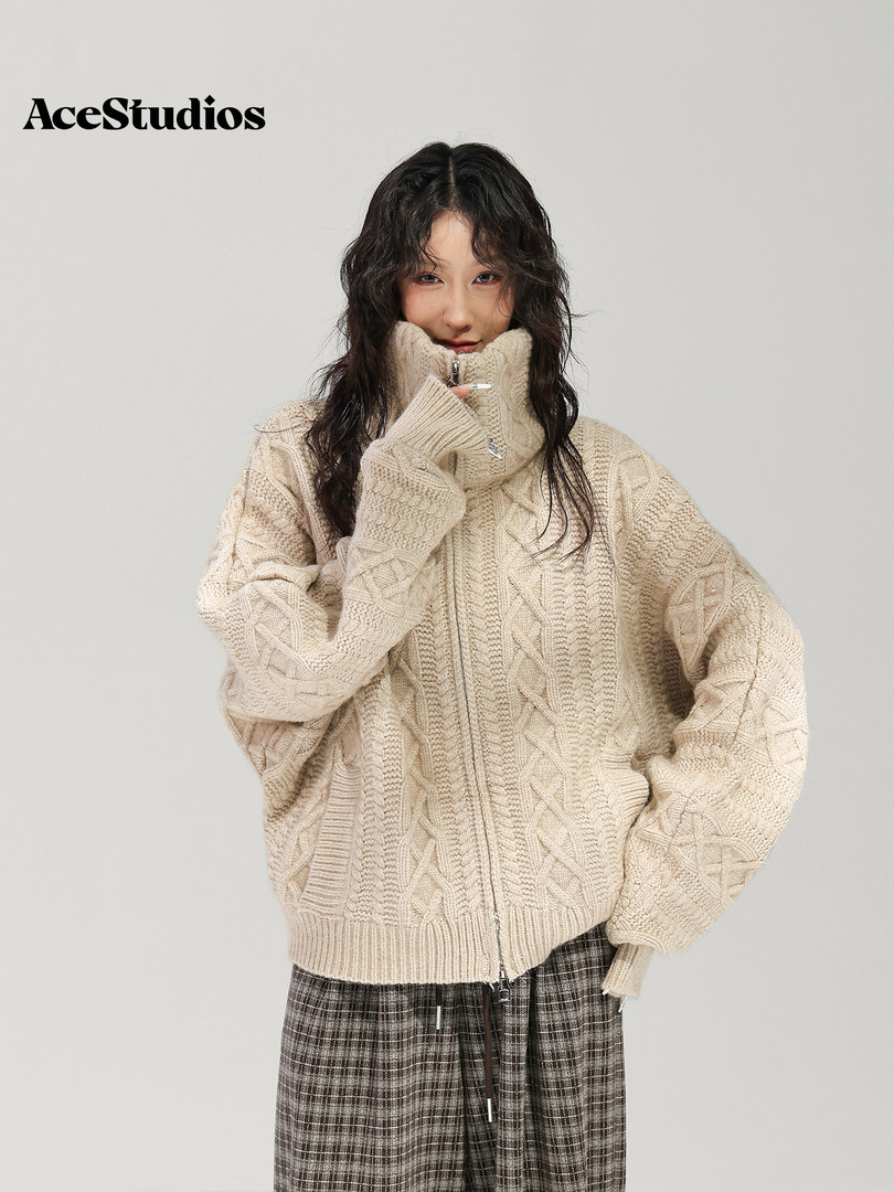 Model wearing a chunky cream cable-knit sweater with plaid bottoms