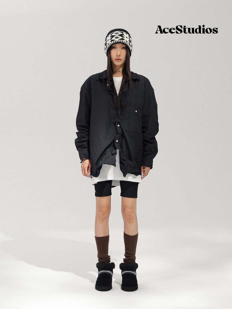 Model wearing a layered black streetwear outfit with a beanie, shorts, leg warmers, and platform boots.
