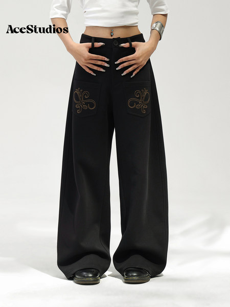 Model wearing black wide-leg pants with decorative embroidered pocket details.