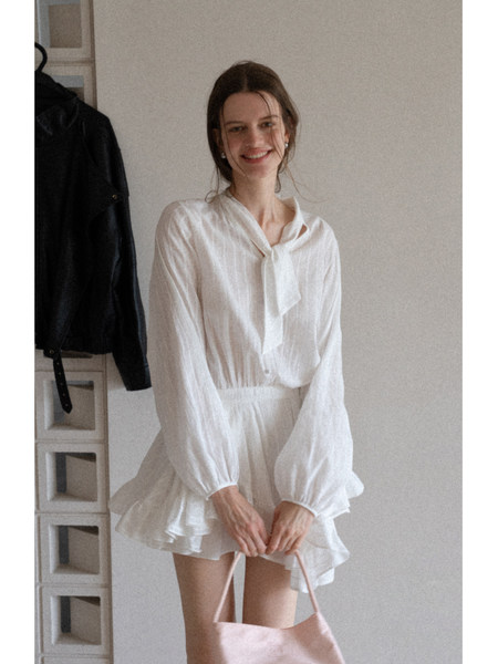 Woman wearing a white lightweight long-sleeve ruffled dress