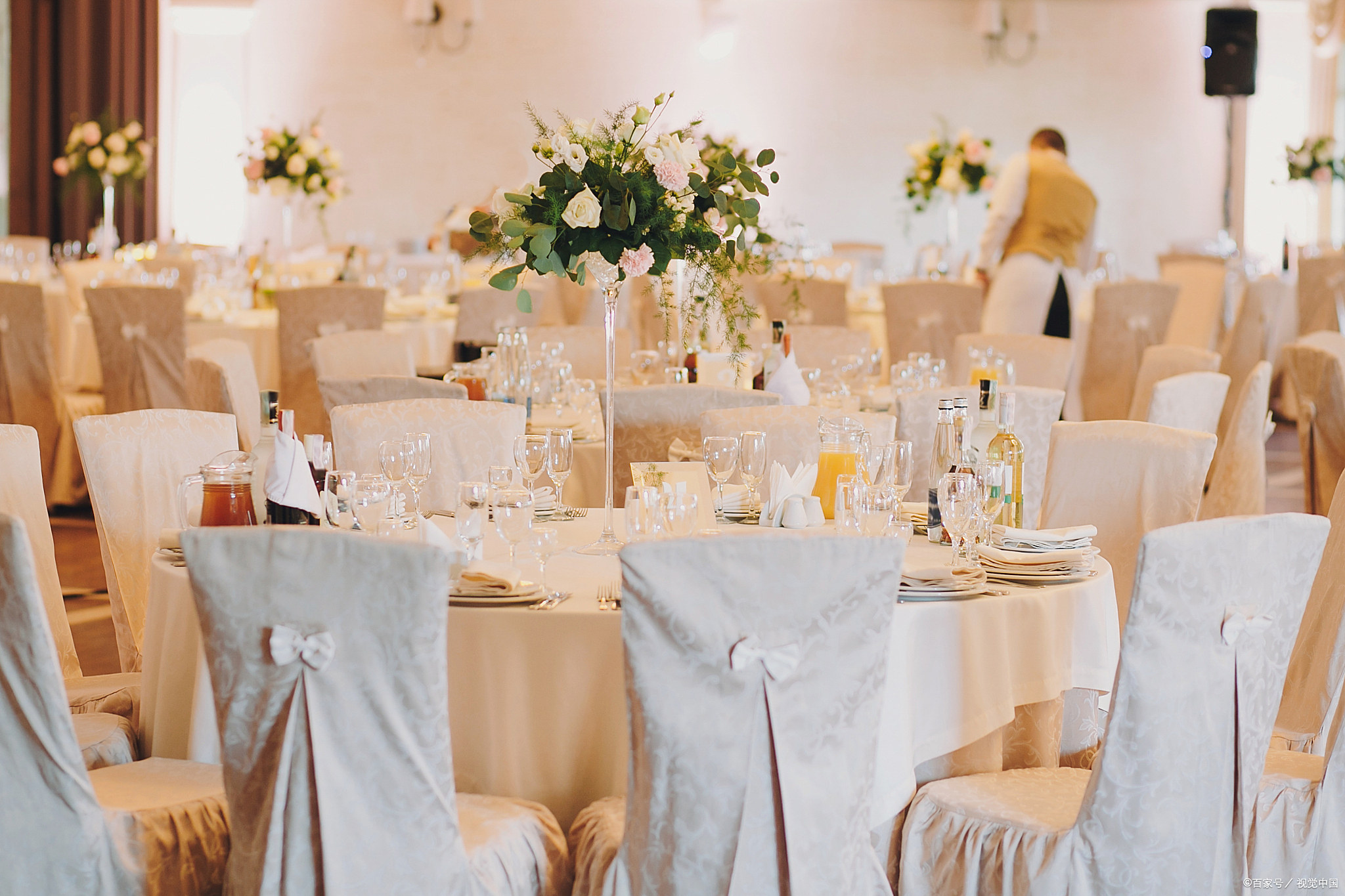 Minimalist wedding table with a neutral tablecloth, simple plates, one stem in a vase, and candles