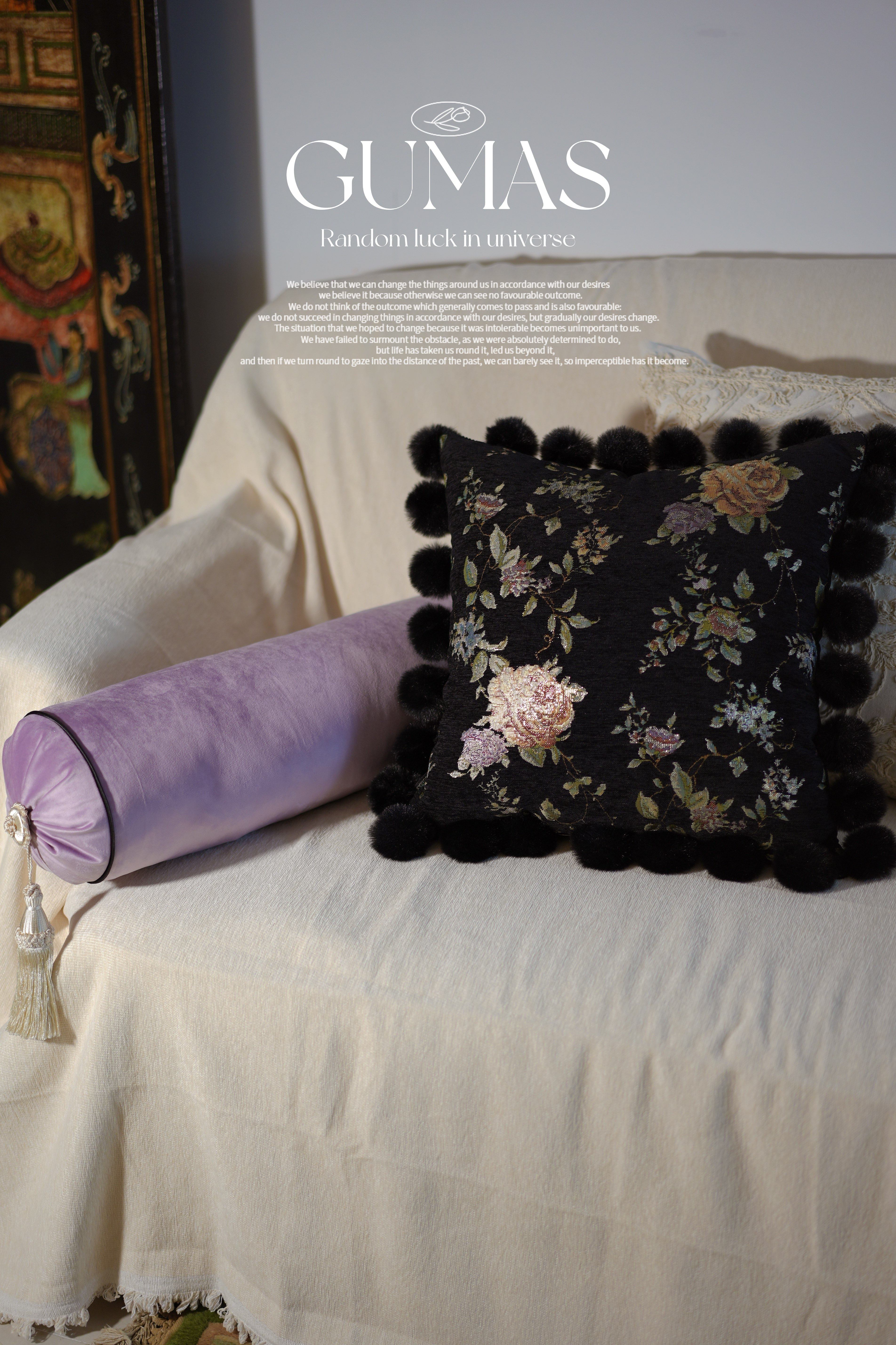 Black decorative pillow with colorful botanical embroidery and black pom-pom edging