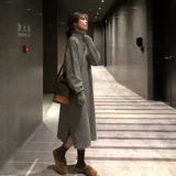 Пальто нового стиля 2025 года с высоким воротником и длинным свитером выше колена с черным трикотажным платьем под ним для осенних и зимних женщин.