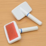 Собака и кошачья расчесывание расчесывало, чтобы снять мех и массировать очищение плюшевой кошки Бики.