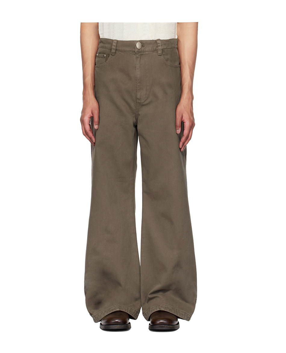 A person models EastLyst’s Retro Distressed Flare Pants in olive green with a relaxed, oversized fit, front pockets, and button closure, paired with dark brown shoes. The background is white and only the upper body is partially visible.