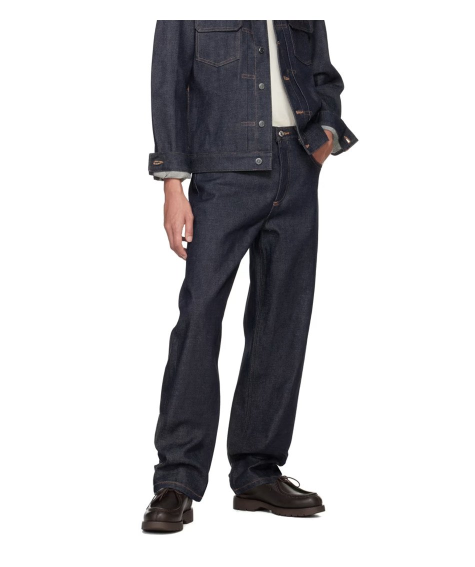 A person wears EastLyst's Classic American Straight Leg Jeans with a dark denim jacket, white shirt, and black shoes, standing with one hand in their pocket against a white background for a timeless, casual look.