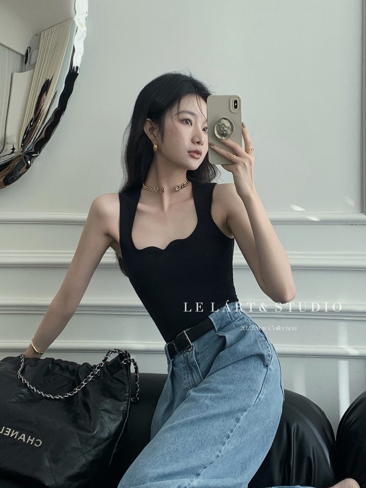 Black sleeveless fitted top styled with light blue jeans and a black handbag