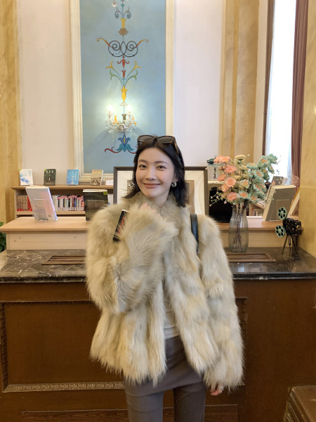 Woman wearing a fluffy beige fur coat indoors
