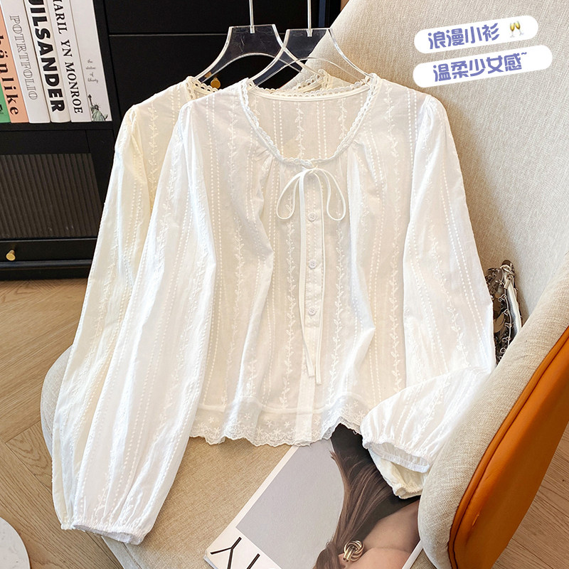 Весной 2025 года появилась новая свободная и тонкая белая кружевная рубашка с круглым вырезом и вышивкой в виде камелии, топ с длинными рукавами и шнуровкой