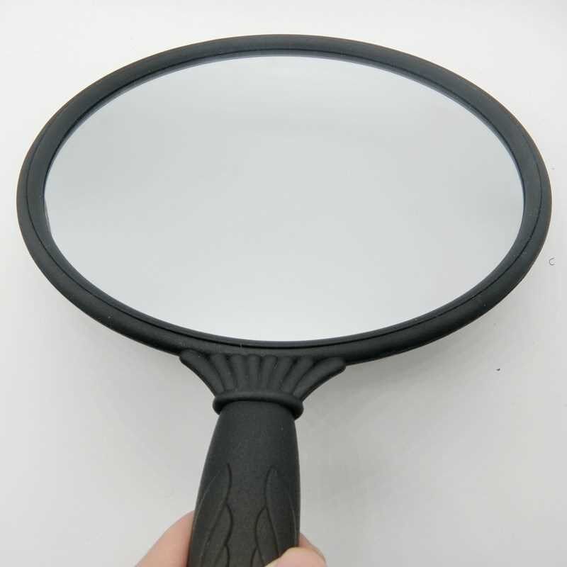 Looking at the mirror at the back of the head, the stylist in the haircut shop looks at the hair behind the round mirror with handle