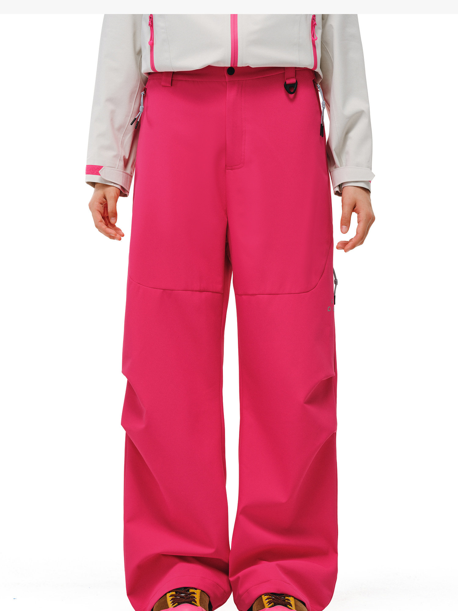 A person is shown from the waist down, wearing EastLyst Softshell Trousers for Hiking in bright pink, featuring a relaxed fit and wide legs. The background is plain white, with a hint of a light gray jacket with pink accents.
