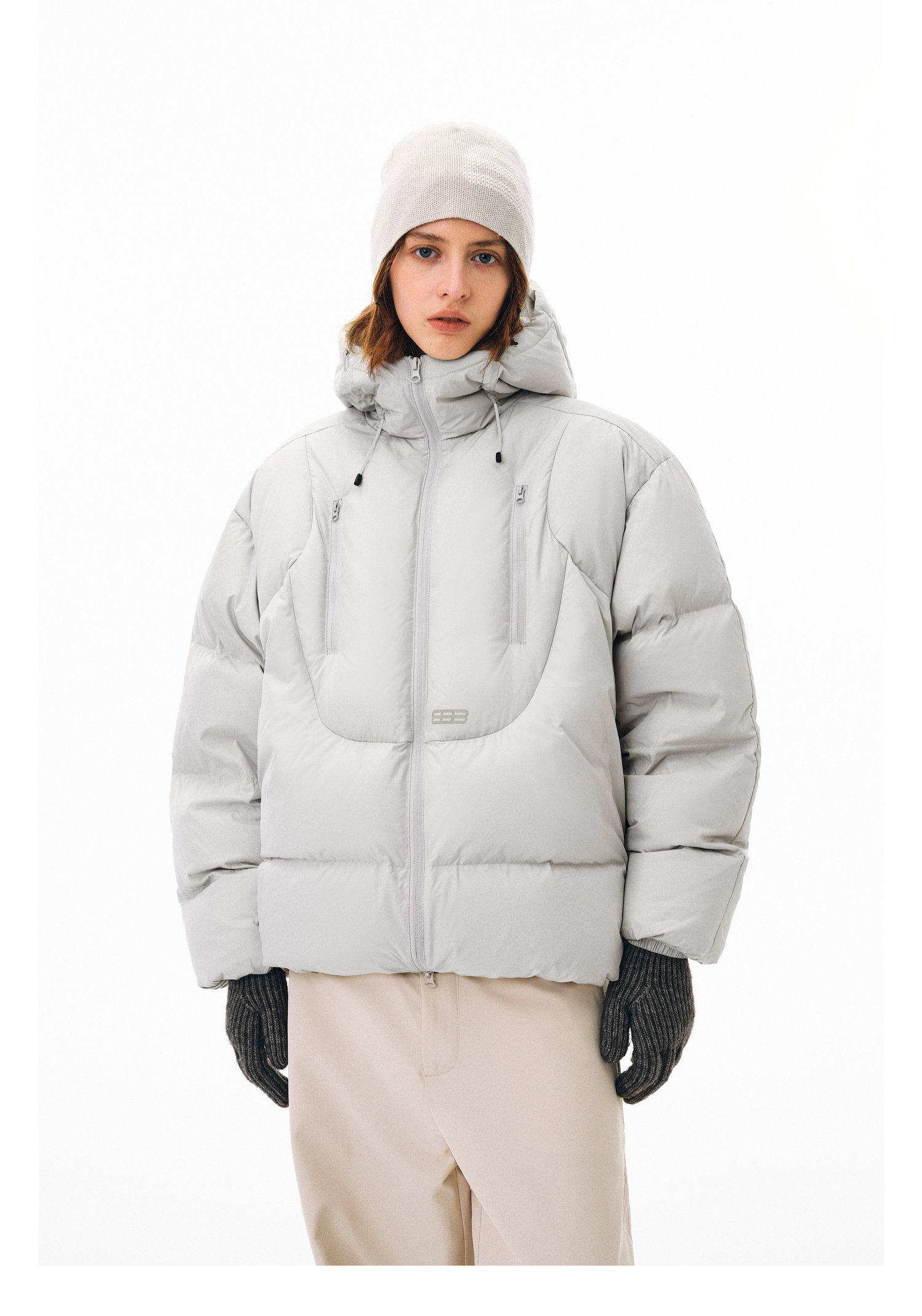 Wearing the EastLyst Fashionable 3D short down jacket in light gray, along with a beige beanie, gray knit gloves, and light pants, a person stands against a plain white background facing forward with a neutral expression.