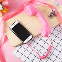 Headphone plug microphone can be stretched and wired to listen to songs connected to pink mobile phone landline earpiece old-fashioned call