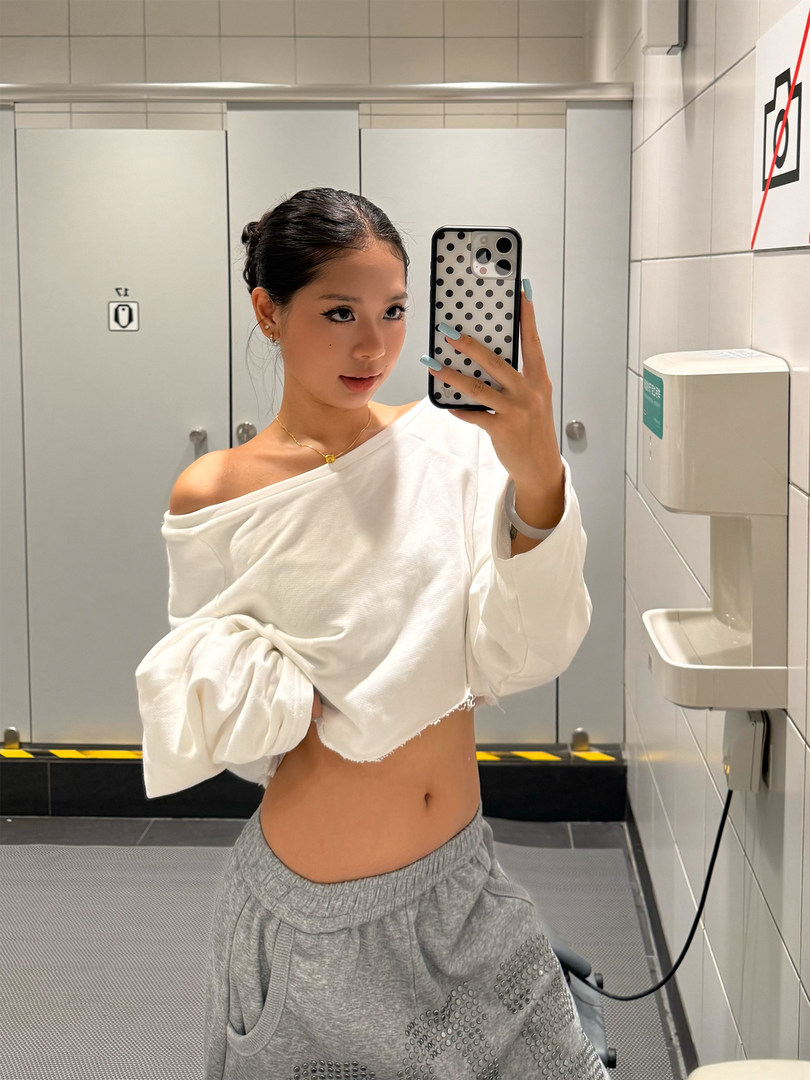 Woman wearing a white off-shoulder cropped top with gray jogger pants