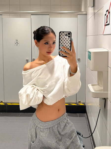 Woman wearing a white off-shoulder cropped top with gray jogger pants