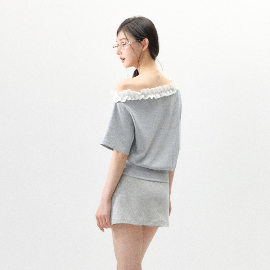 Woman wearing a gray off-shoulder lounge set with white ruffle trim