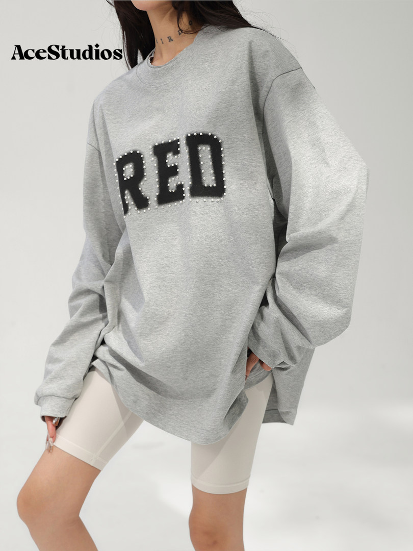 Model wearing an oversized gray sweatshirt with bold black RED lettering.