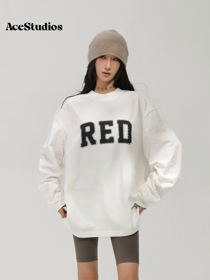 Model wearing an oversized white RED sweatshirt with a knit beanie and fitted shorts.