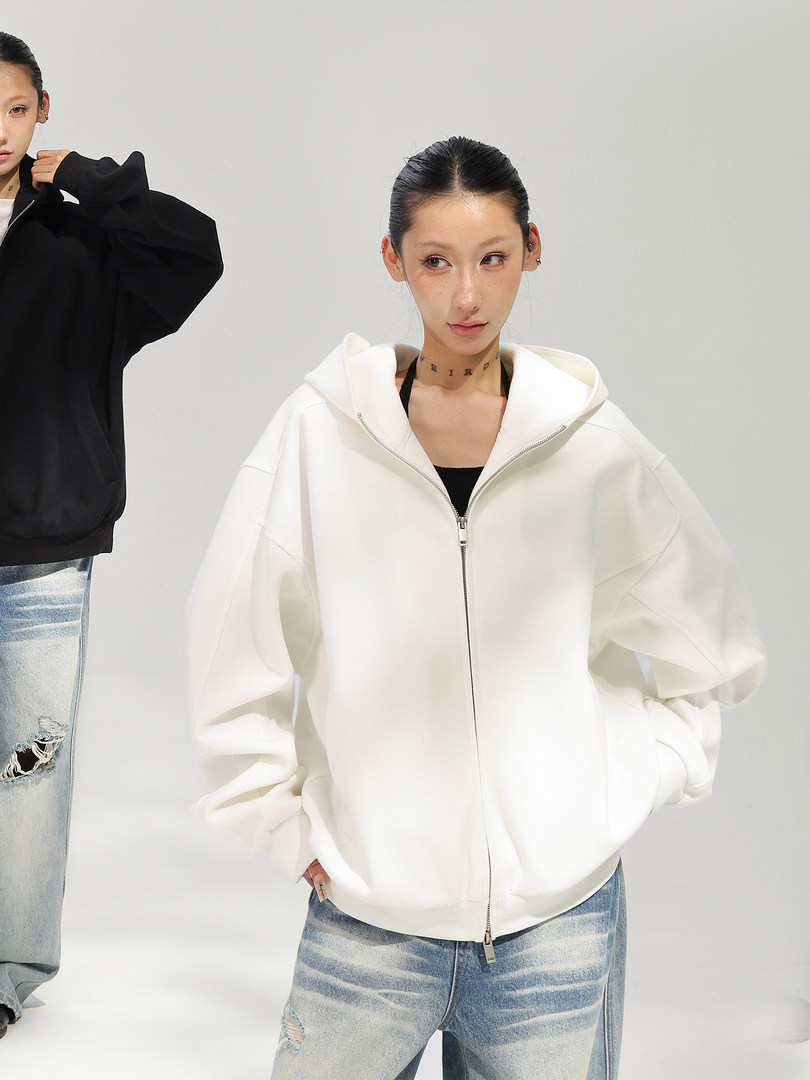 Model wearing a white zip-up hooded jacket with distressed blue jeans