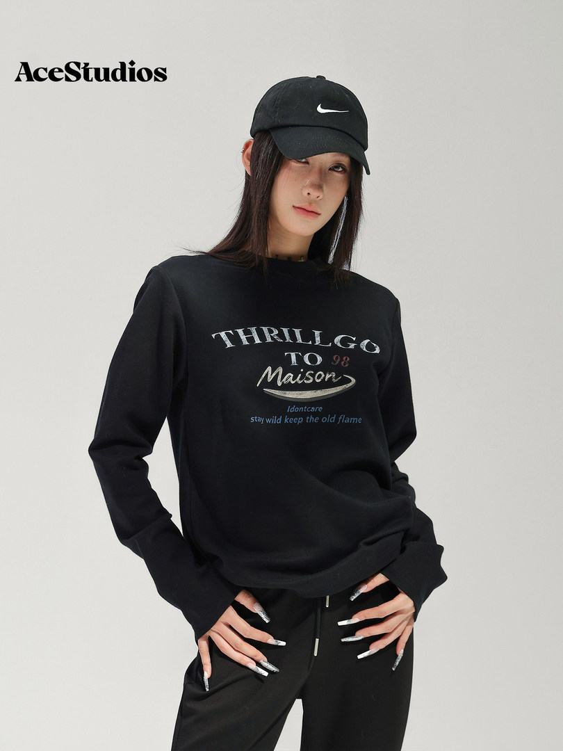 Model wearing a black graphic sweatshirt, black pants, and black Nike cap.