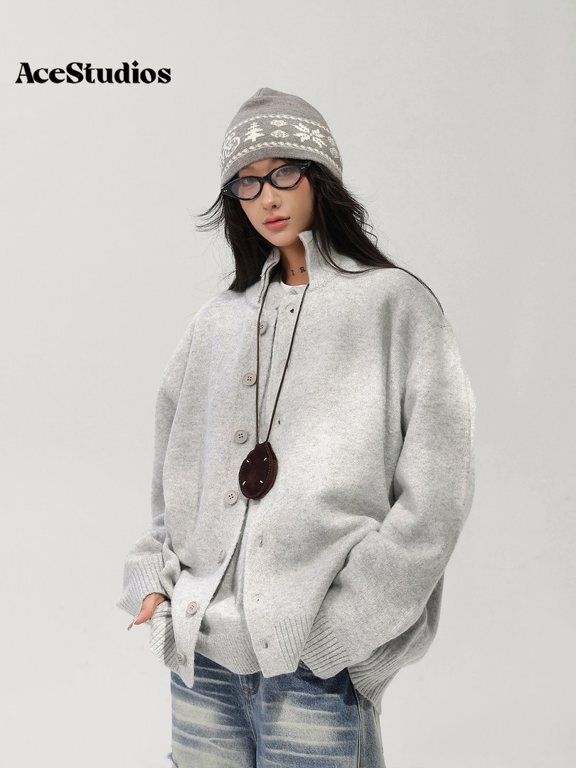 Model wearing a gray knit cardigan, patterned beanie, glasses, and jeans.