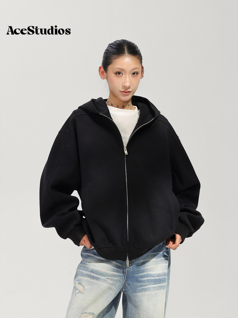 Model wearing a black zip-up hooded jacket with relaxed jeans