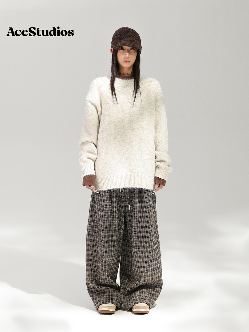 Model wearing a cream knit sweater with wide-leg patterned trousers