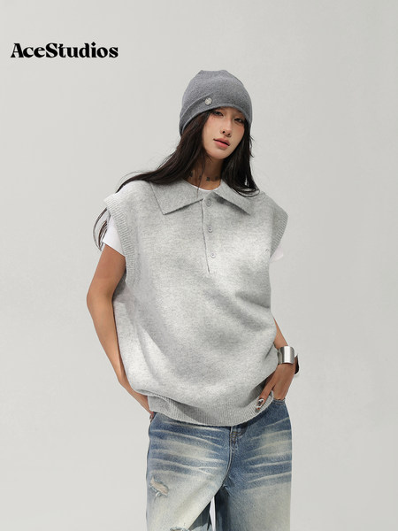 Model wearing a gray knit sleeveless pullover with jeans and a matching beanie.