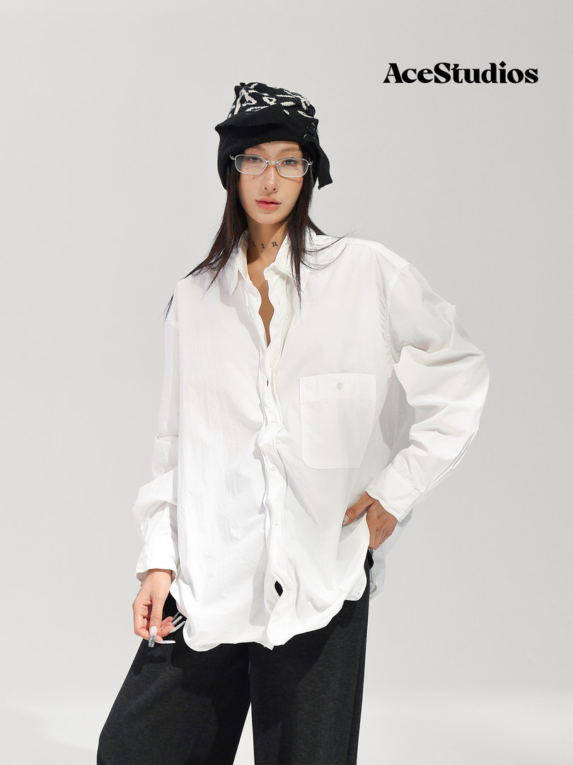 Model wearing a white oversized button-up shirt with black pants and a black hat