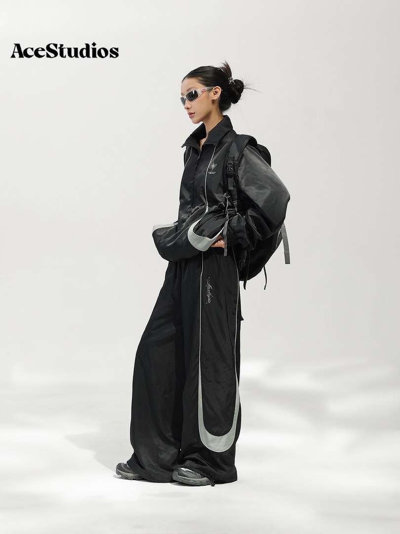 Model wearing a black oversized streetwear outfit with a backpack and sunglasses.