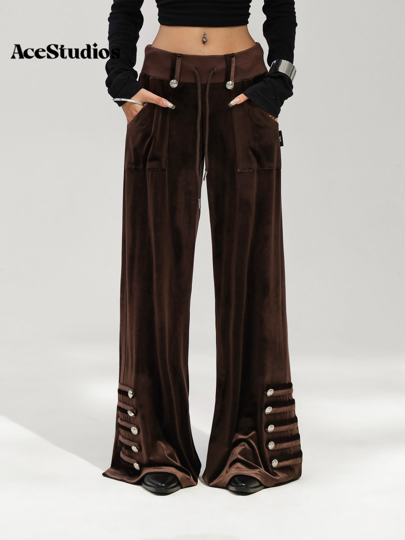 Model wearing dark brown wide-leg cargo pants with decorative zippers and straps