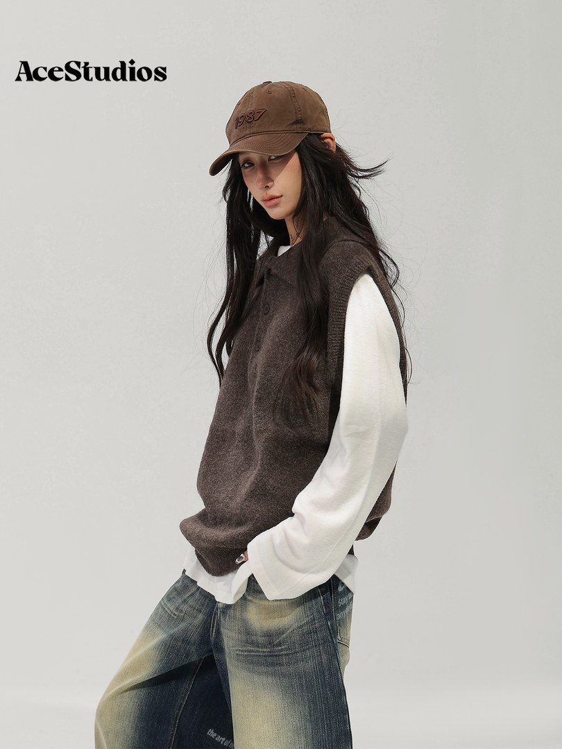 Model wearing a brown textured vest over a white long-sleeve top with distressed jeans and a brown cap.