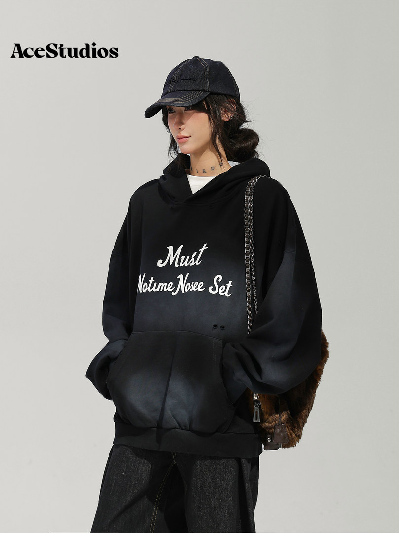 Model wearing an oversized black graphic hoodie with a cap and shoulder bag