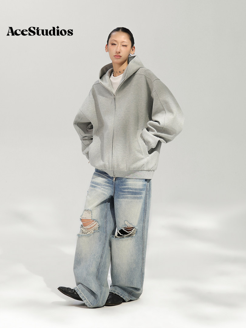 Model wearing a gray zip-up hoodie and distressed wide-leg jeans