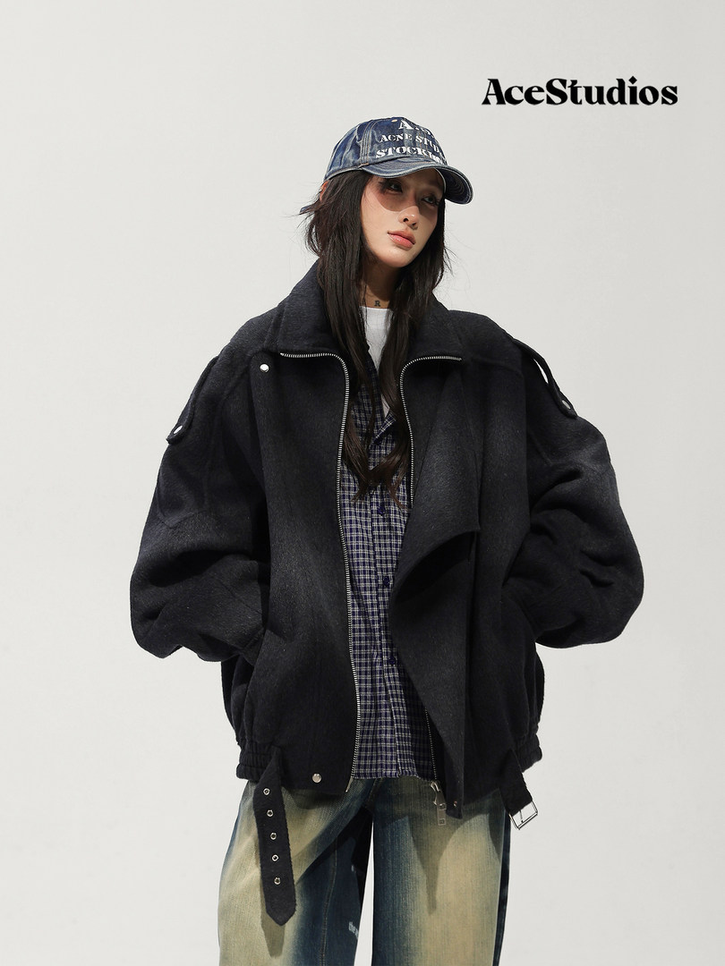 Model wearing a black oversized jacket with a graphic cap and distressed jeans.