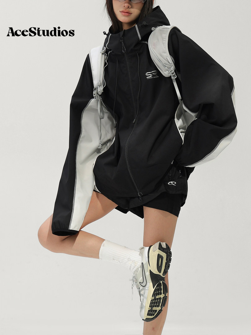 Model wearing a black sporty windbreaker outfit with shorts and sneakers