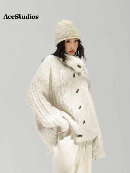 Model wearing a cream chunky knit sweater and matching beanie