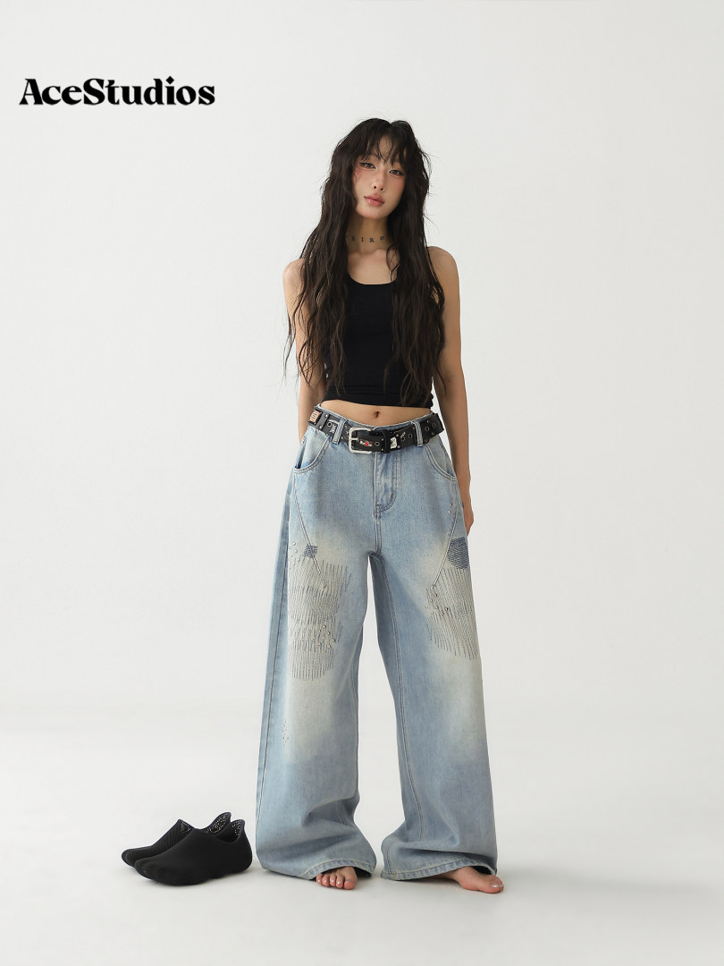 Model wearing wide-leg distressed light-wash jeans with a black tank top and black sneakers.