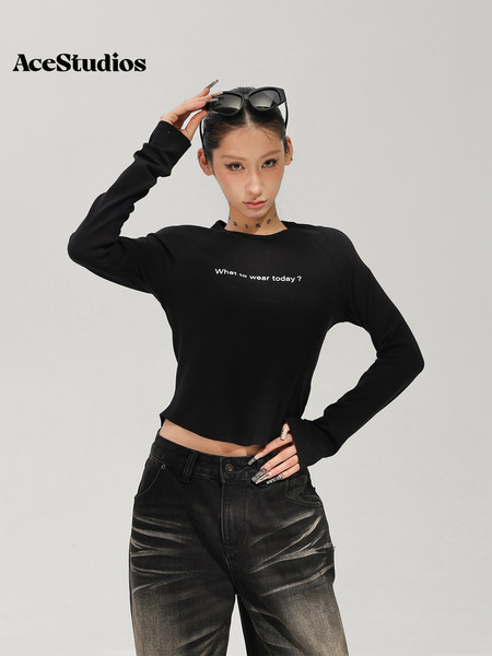 Model wearing a black long-sleeve cropped top and distressed black jeans