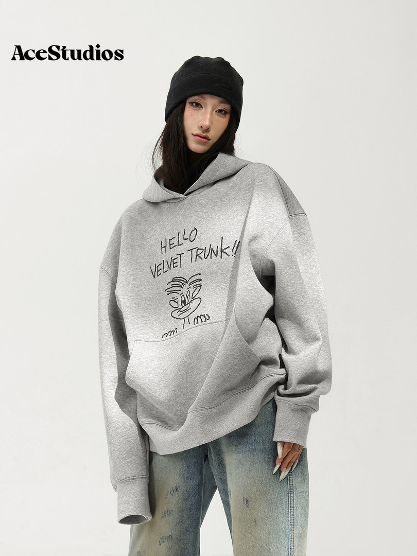 Model wearing a gray graphic hoodie with distressed jeans and a black knit beanie