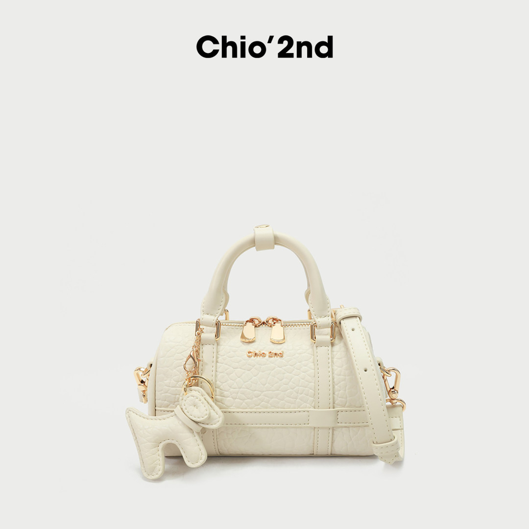 Cream mini handbag with gold-tone hardware and shoulder strap on white background
