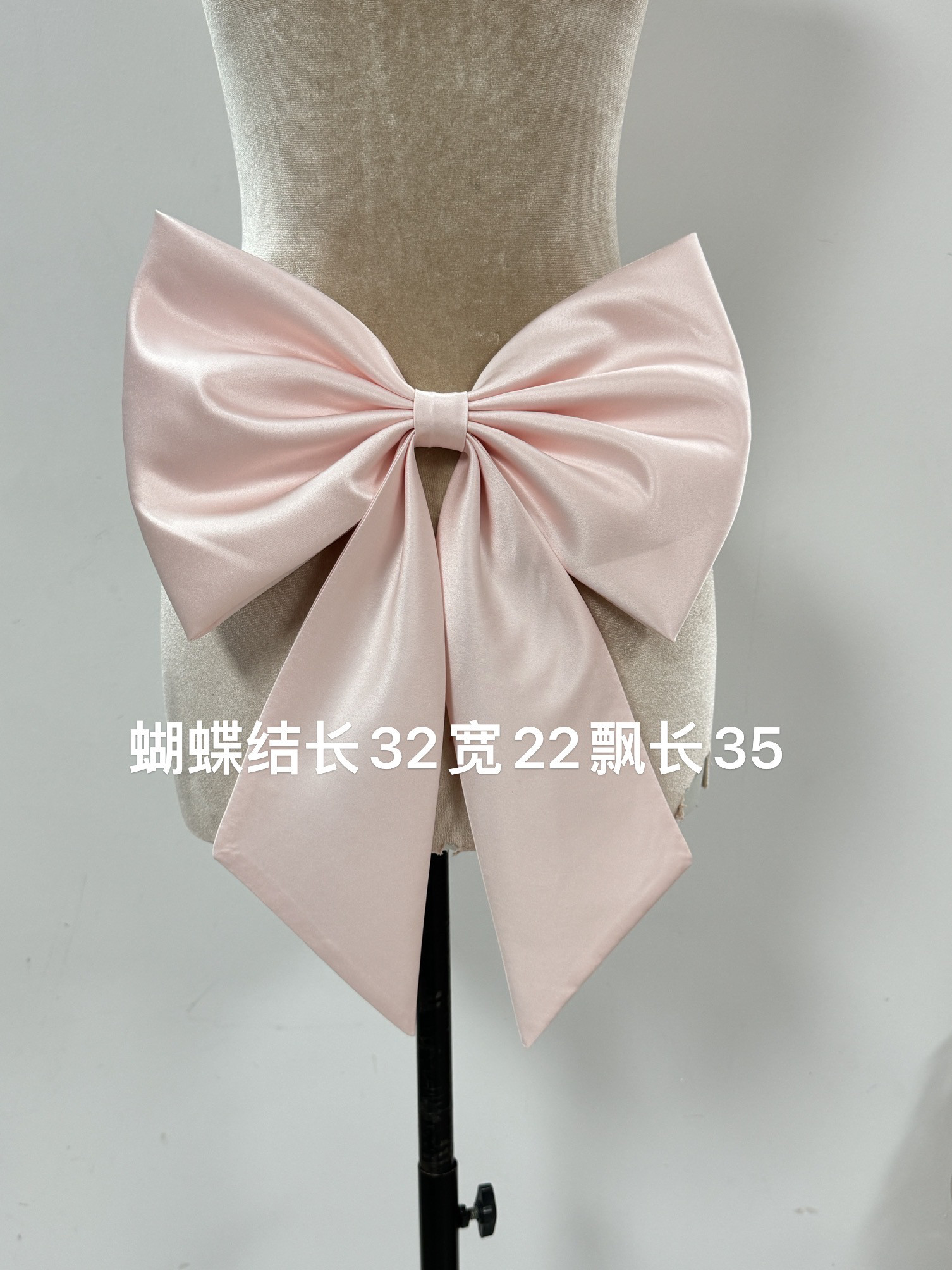 Soft, blush pink dress with a bow, featuring a large, embellished back  detail. finished with a