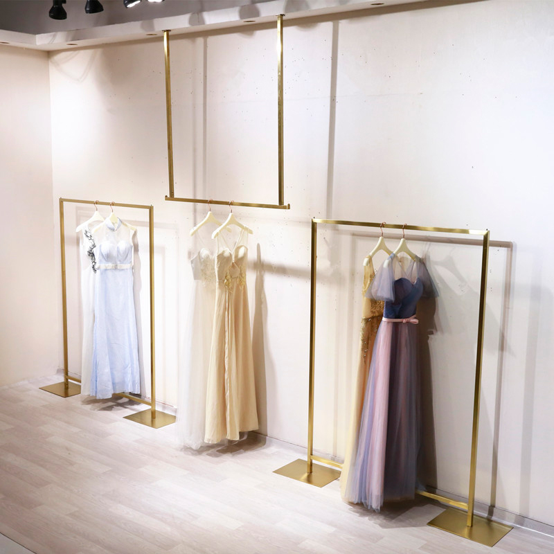 Clothing Store Hanger Racks shelves Stainless Steel Rose Gold Titanium Alloy Suspended Rings are hanging off the middle island shelf